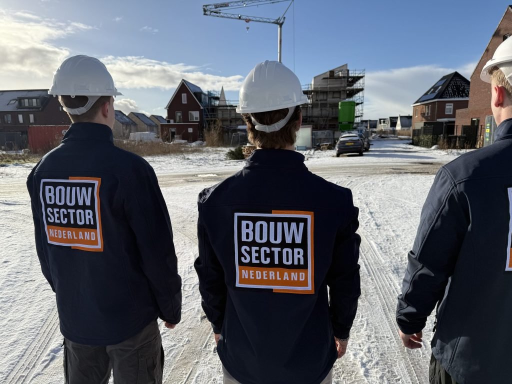 Vakmensen van Bouwsector Nederland met witte helm op een besneeuwde straat tussen bakstenen woningen